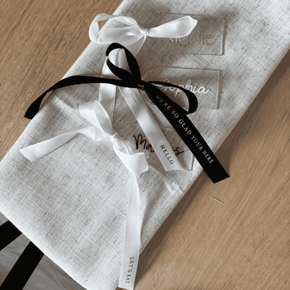 Clear acrylic wedding place settings with black and white ribbon details, styled for modern wedding table settings