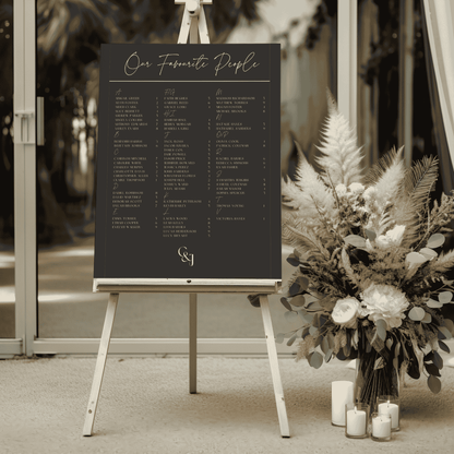Black Tie wedding seating chart styled at reception entrance beside neutral florals and candles