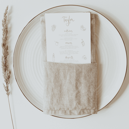 Candelabra menu tucked inside neutral linen napkin, styled on a ceramic plate with minimal table décor