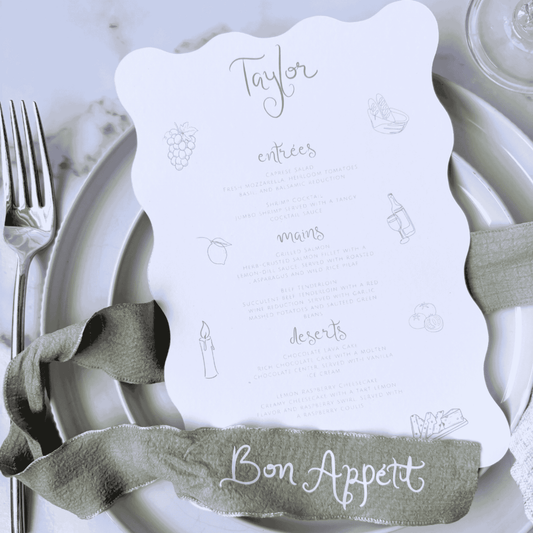 Candelabra menu with scalloped edge, styled on plate with personalised green ribbon reading Bon Appétit