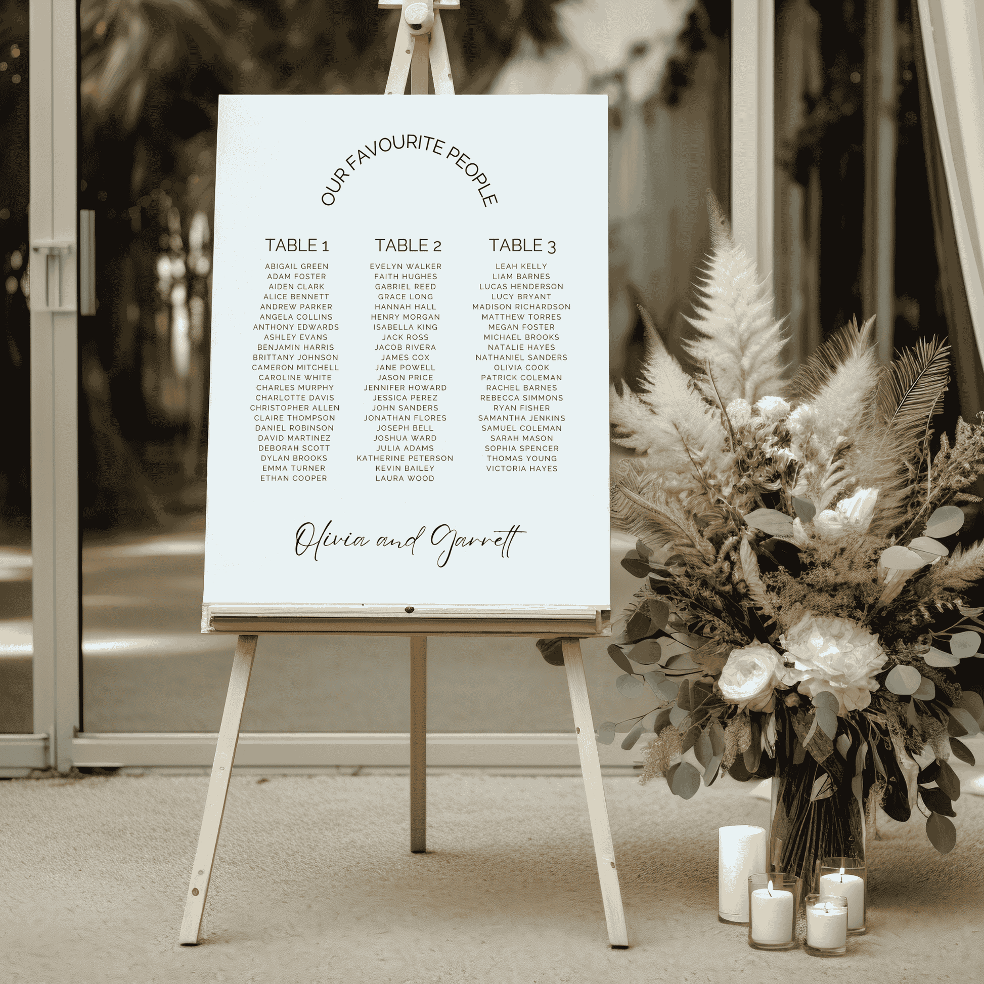 Classic wedding seating chart styled at reception entrance beside neutral floral arrangement and candles