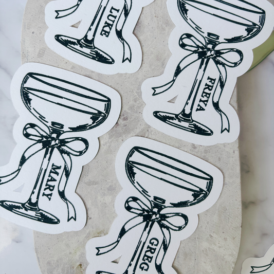 Flat lay of illustrated cocktail place cards with guest names, styled for wedding reception table settings