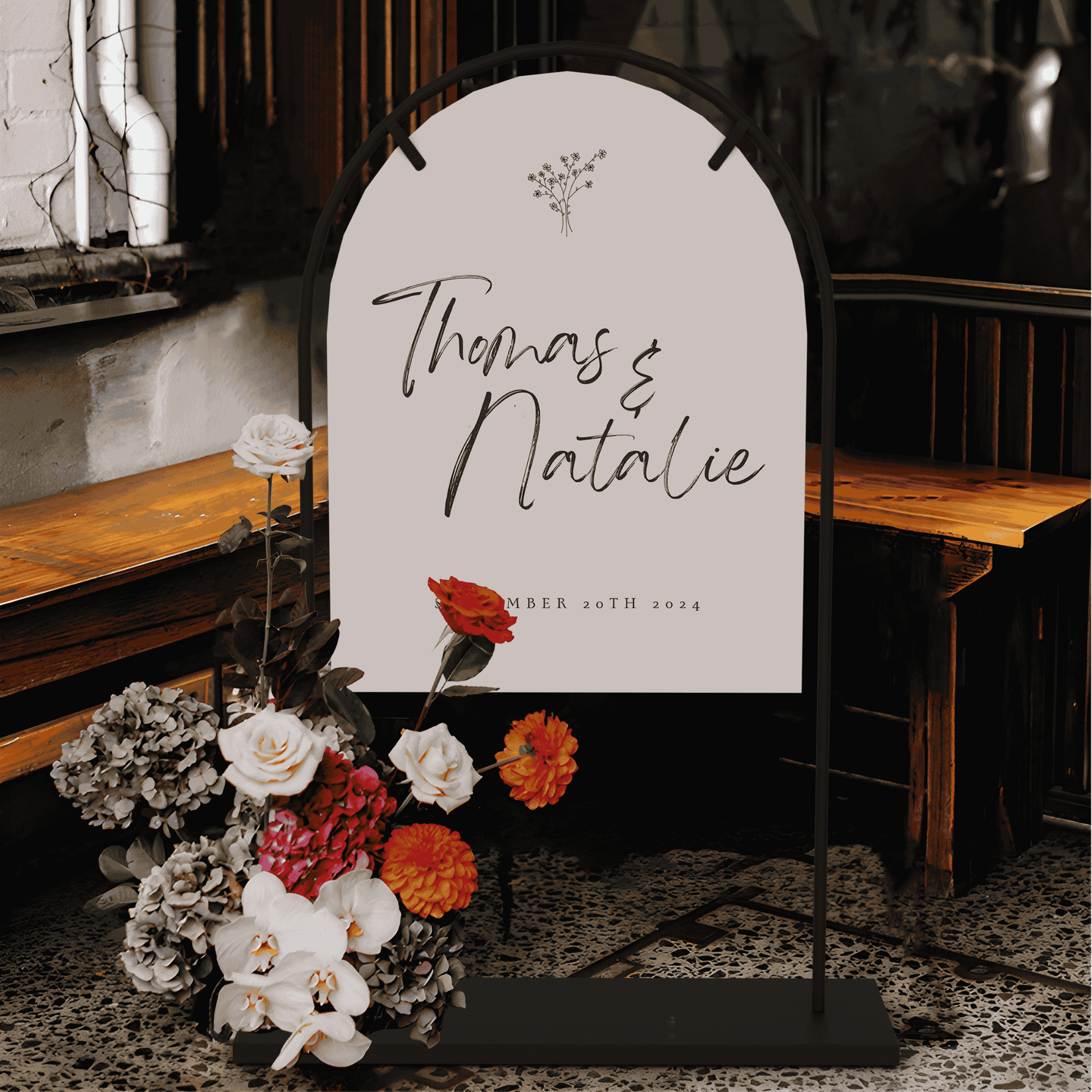 Daisy wedding welcome sign displayed on arch stand with florals styled for wedding signage at indoor wedding event