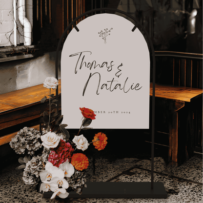 Daisy wedding welcome sign displayed on arch stand with florals styled for wedding signage at indoor wedding event