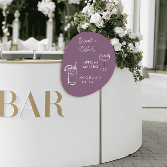 Handwritten signature cocktails bar sign displayed at outdoor wedding bar with floral styling, cocktail menu signage for wedding receptions
