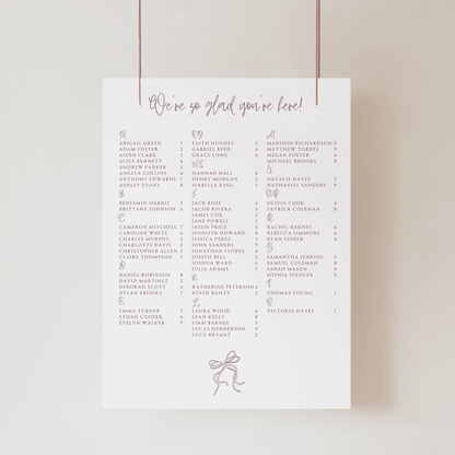 Close-up of handwritten wedding seating sign with flowing script heading and guest list layout
