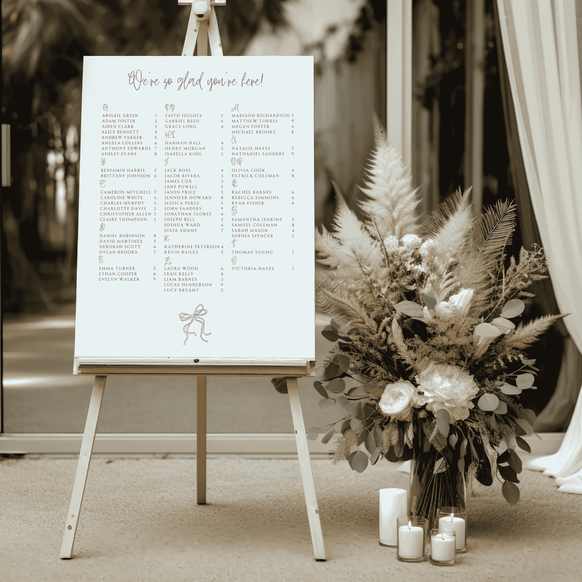 Handwritten wedding seating chart styled at venue entrance with dried florals and candles