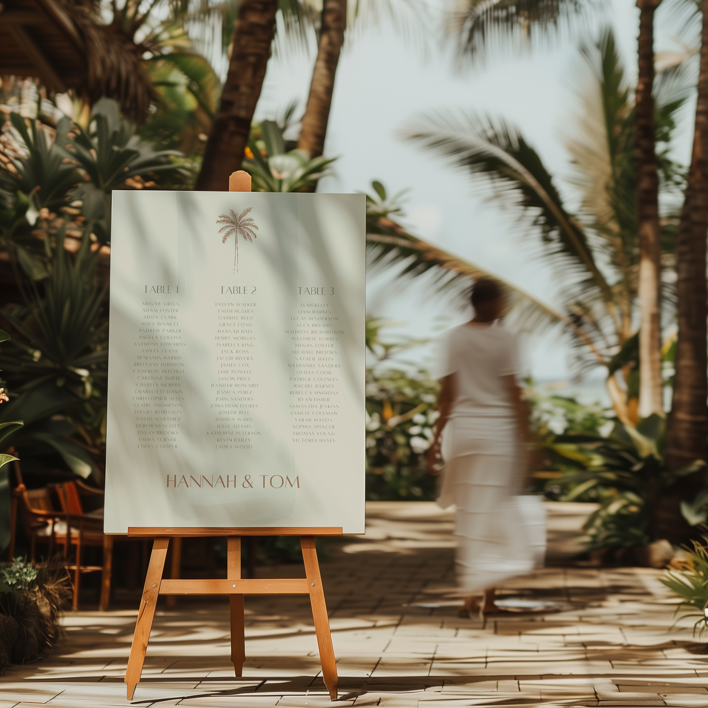 Palm wedding seating chart on easel, styled in tropical beach setting with palm trees