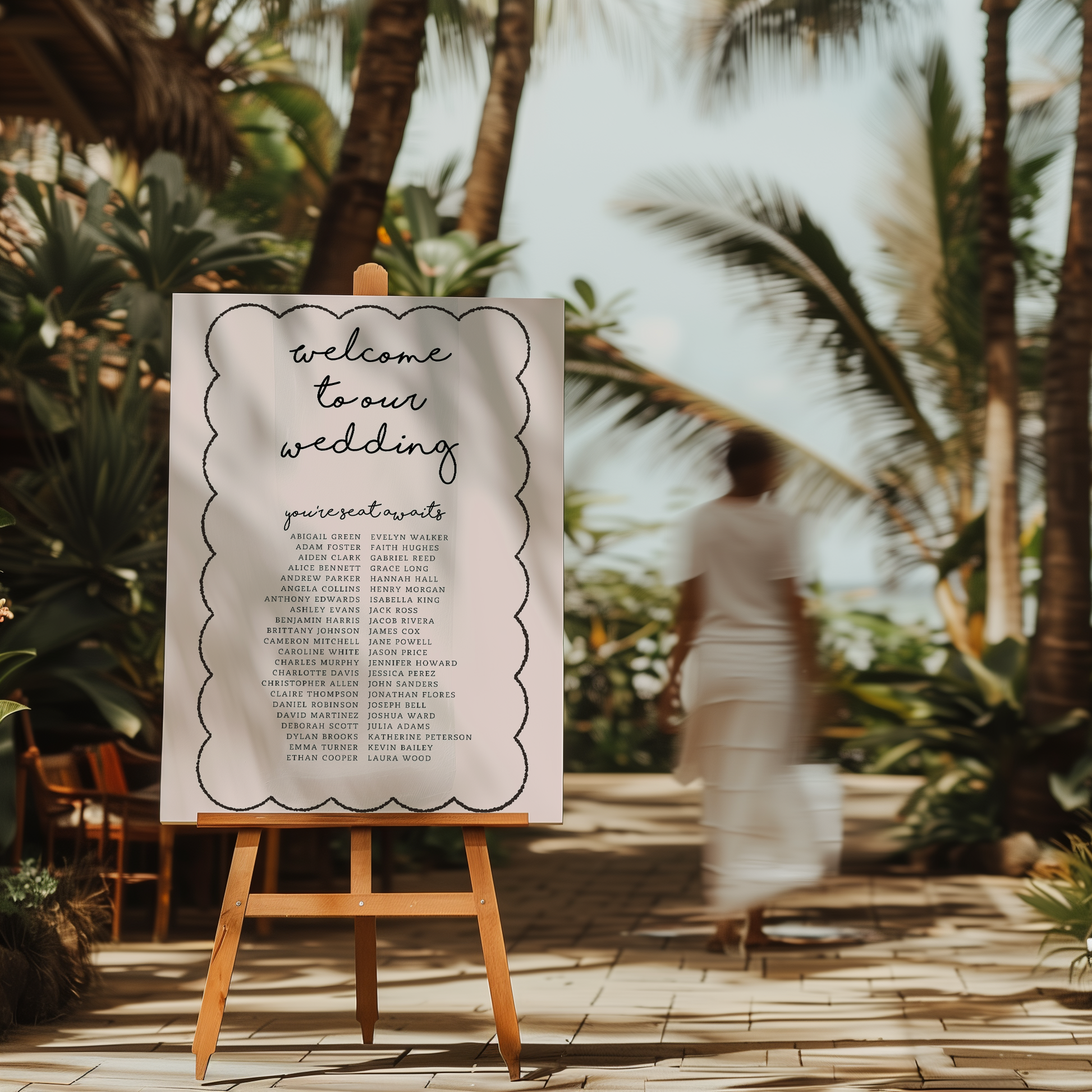 Paris wedding seating chart on easel, styled in tropical beach setting with palm trees