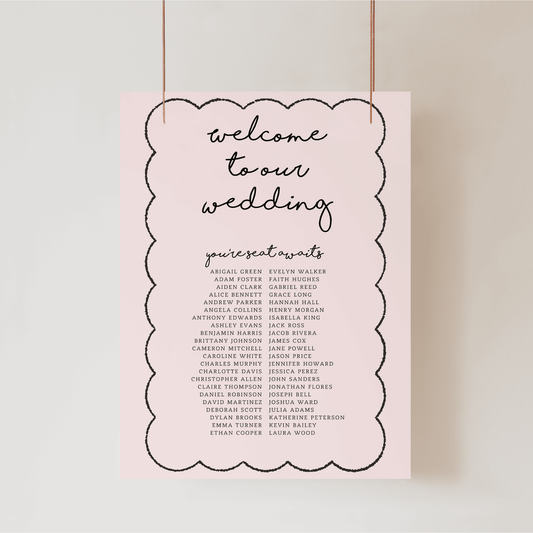 Close-up of Paris wedding seating chart with decorative border, blush background and script heading