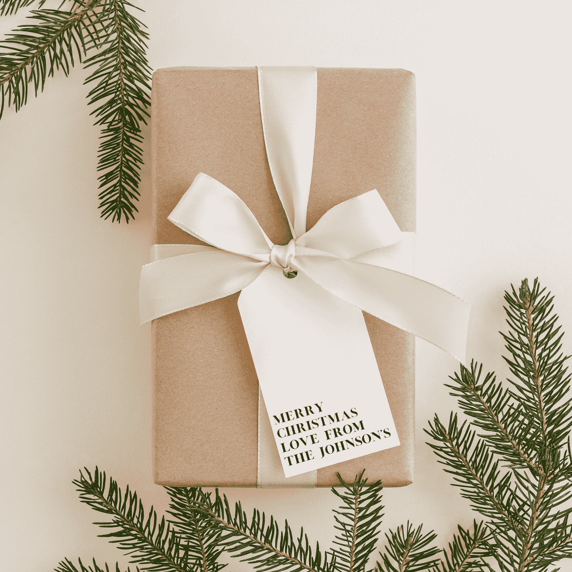 Personalised Christmas gift tag tied to wrapped present, styled with wedding stationery and invitation suite details