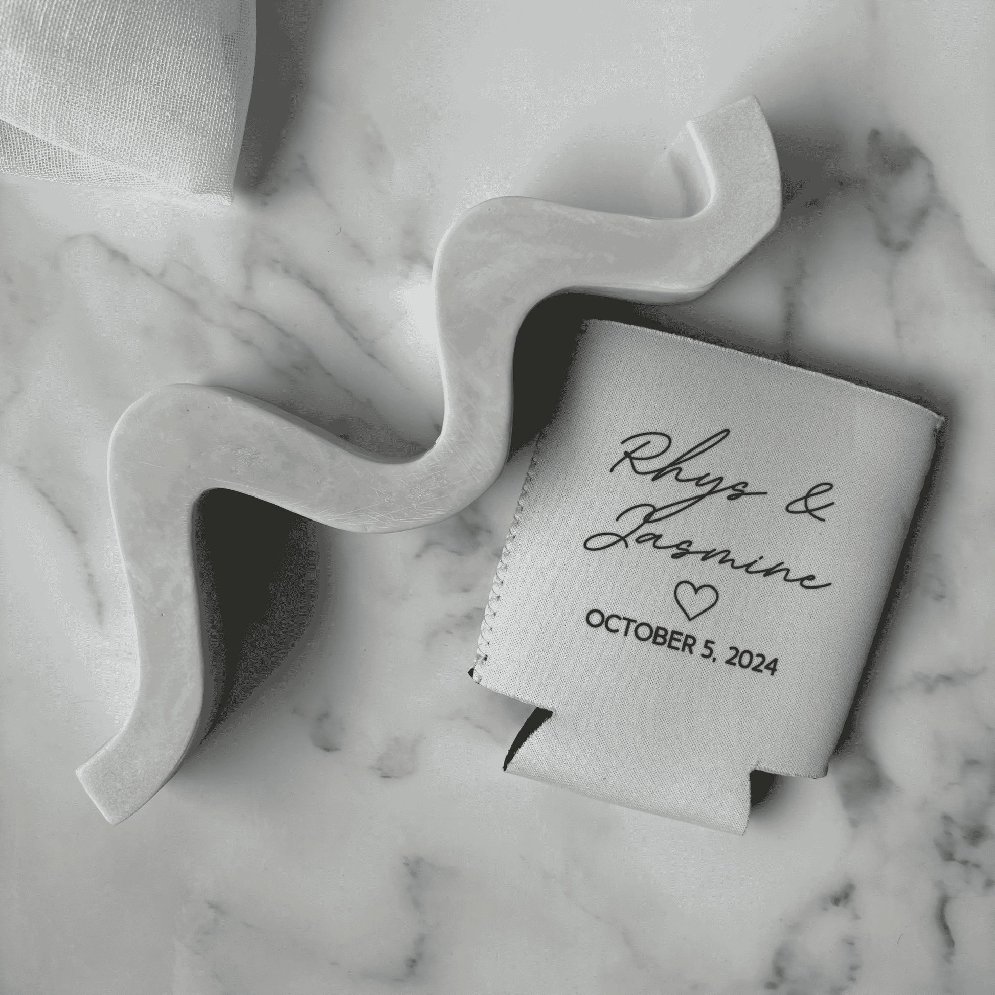 Custom wedding stubby holder featuring names and wedding date, styled as wedding favours alongside modern wedding stationery