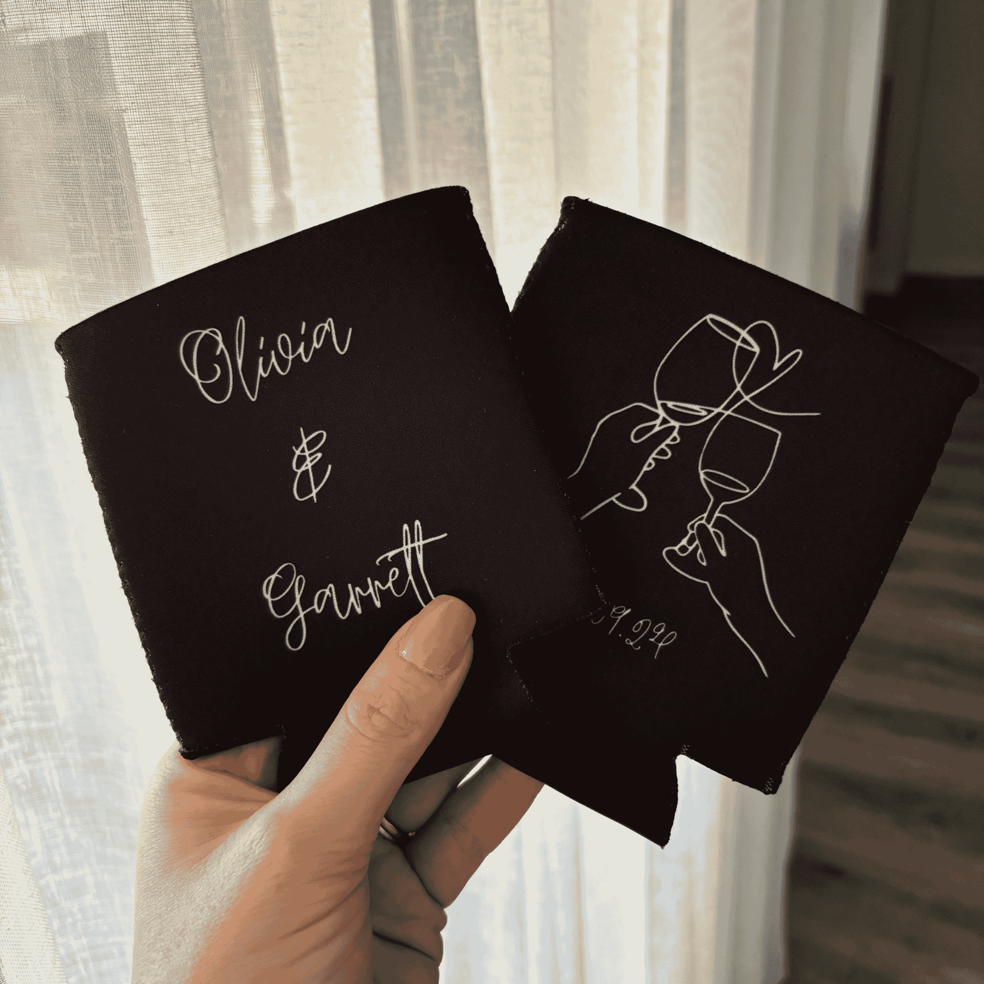 Personalised black wedding stubby holder held in hand showing custom couple names for wedding favours