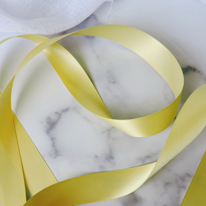 Buttercup yellow satin ribbon for wedding invitations and place settings, styled on marble background