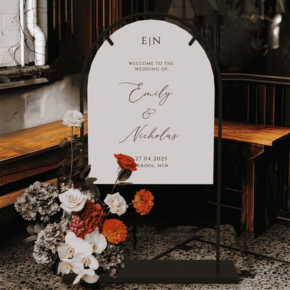 Romance wedding welcome sign displayed on arch stand with modern floral arrangement at indoor reception entrance