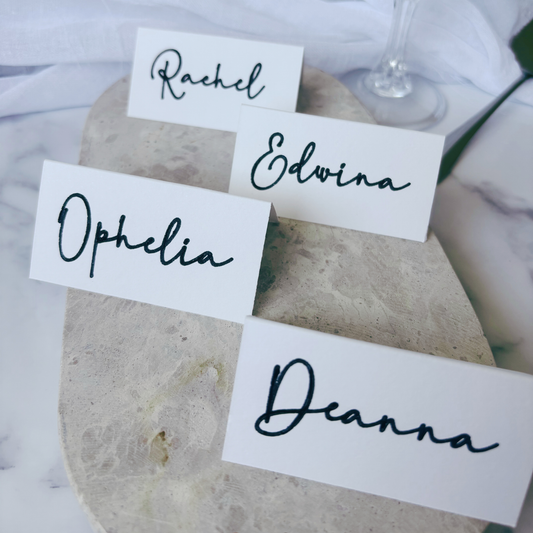 Close-up of white tent fold place cards with handwritten names, styled on wedding table setting